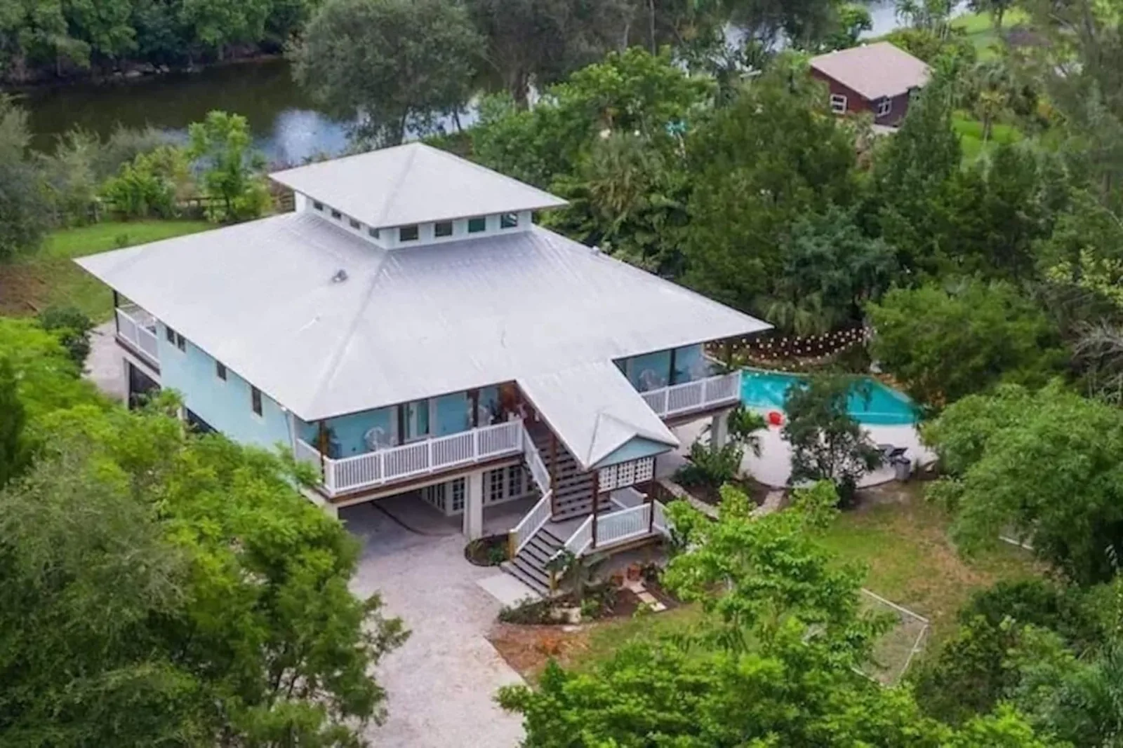 Aerial view of the white metal roof and porches among tropical trees