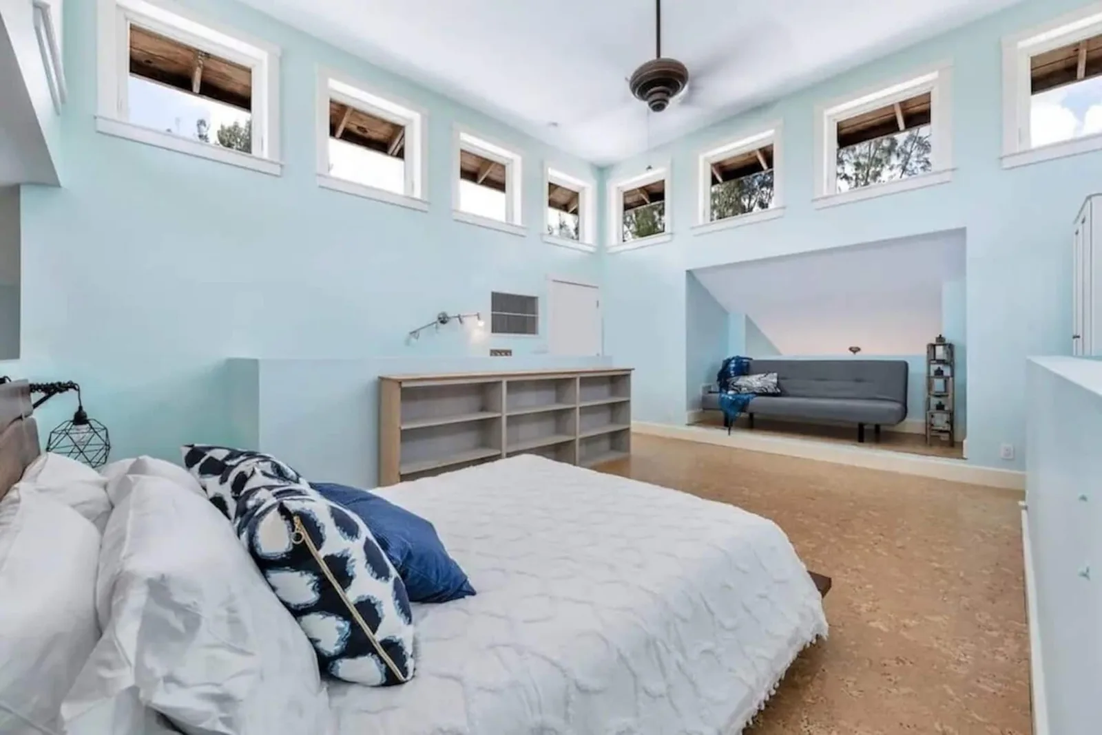 Loft with a queen bed under a row of high windows