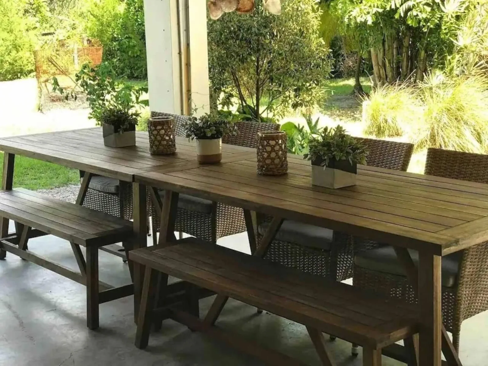 Long outdoor dining table set with candles and plants