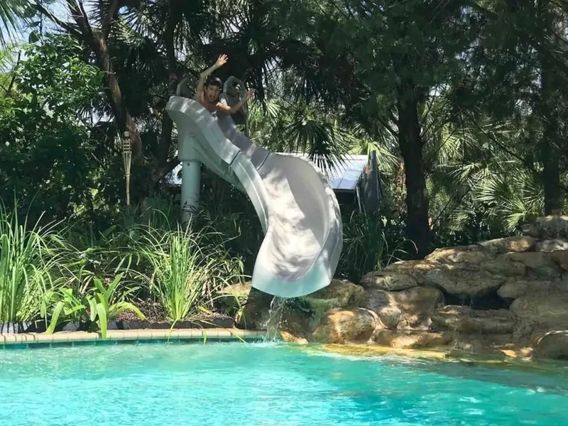 Water slide curving into the pool over the rock waterfall