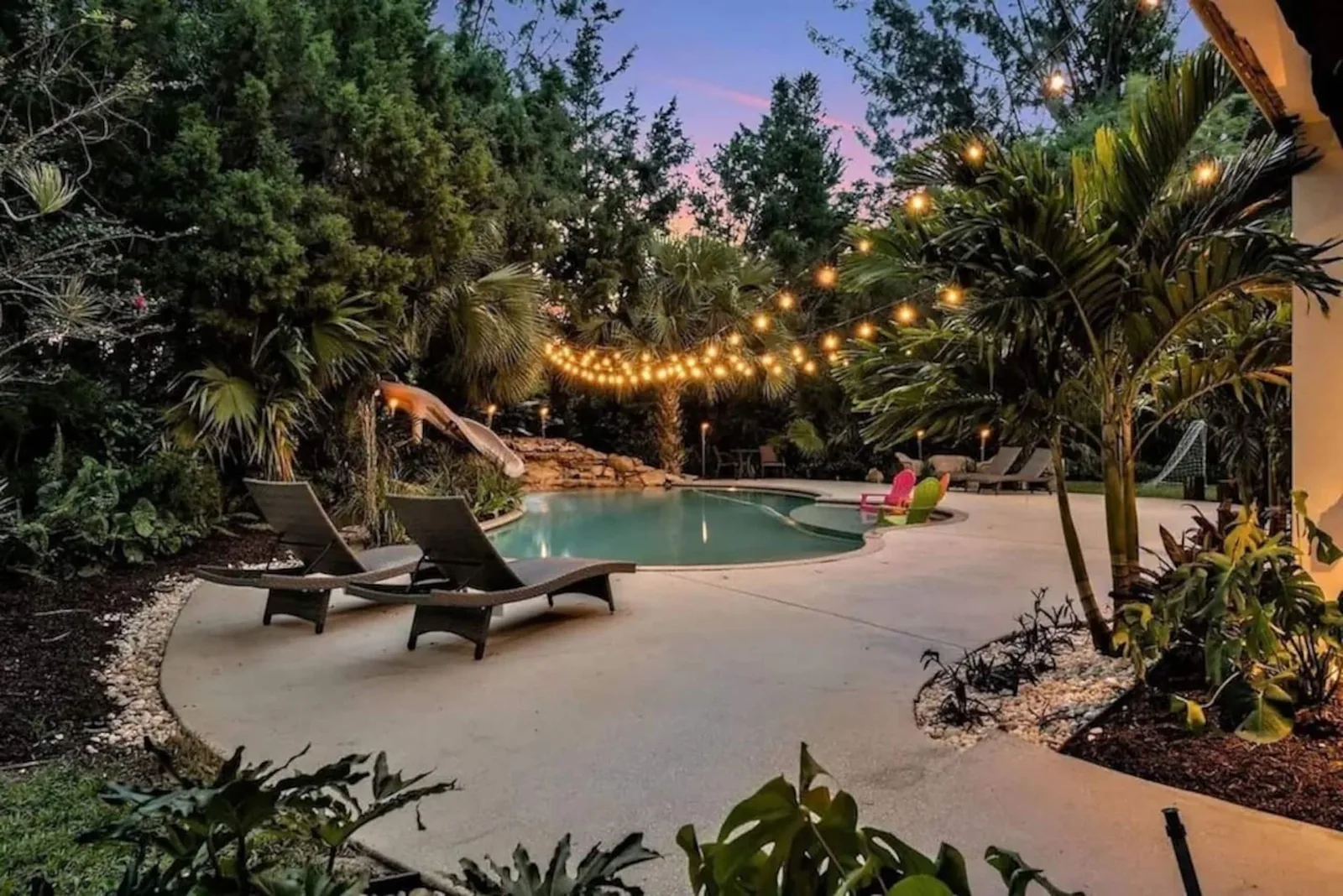 Pool deck at dusk with loungers under string lights