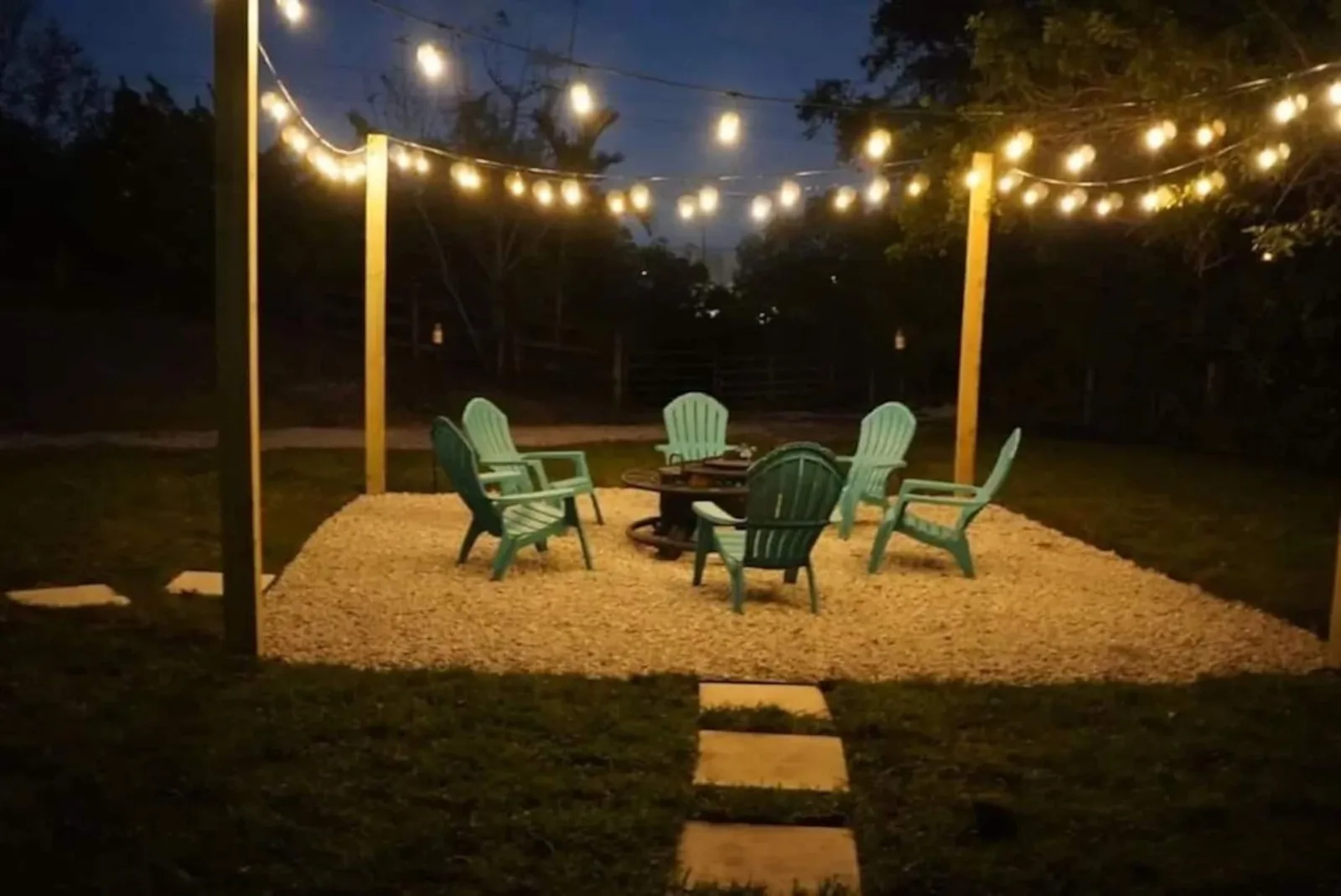Fire pit with Adirondack chairs under string lights at night