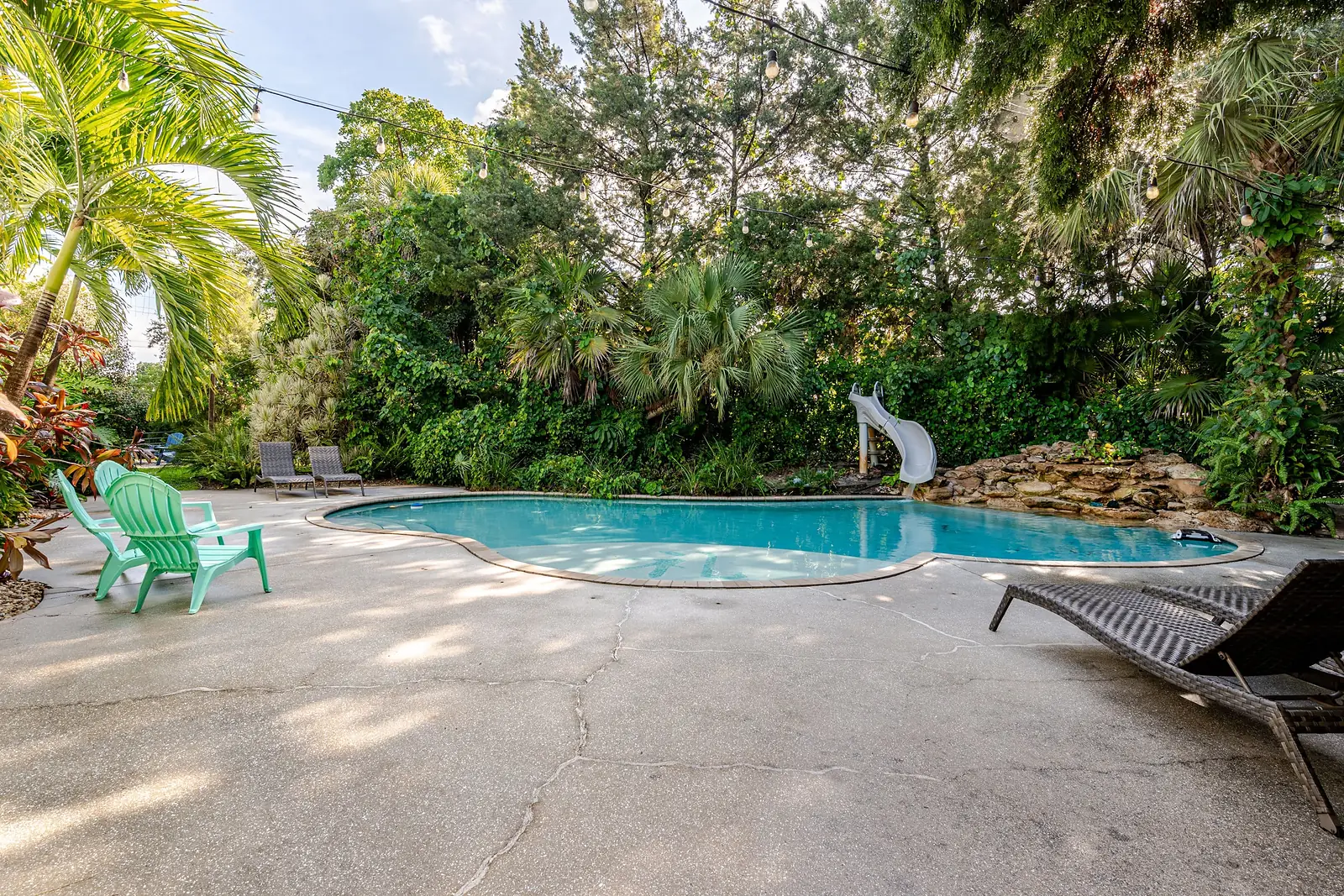 Pool deck with loungers and green Adirondack chairs
