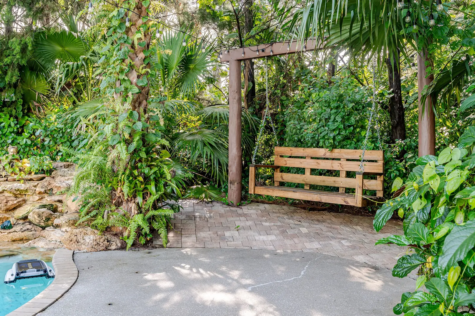 Wooden swing among tropical plants