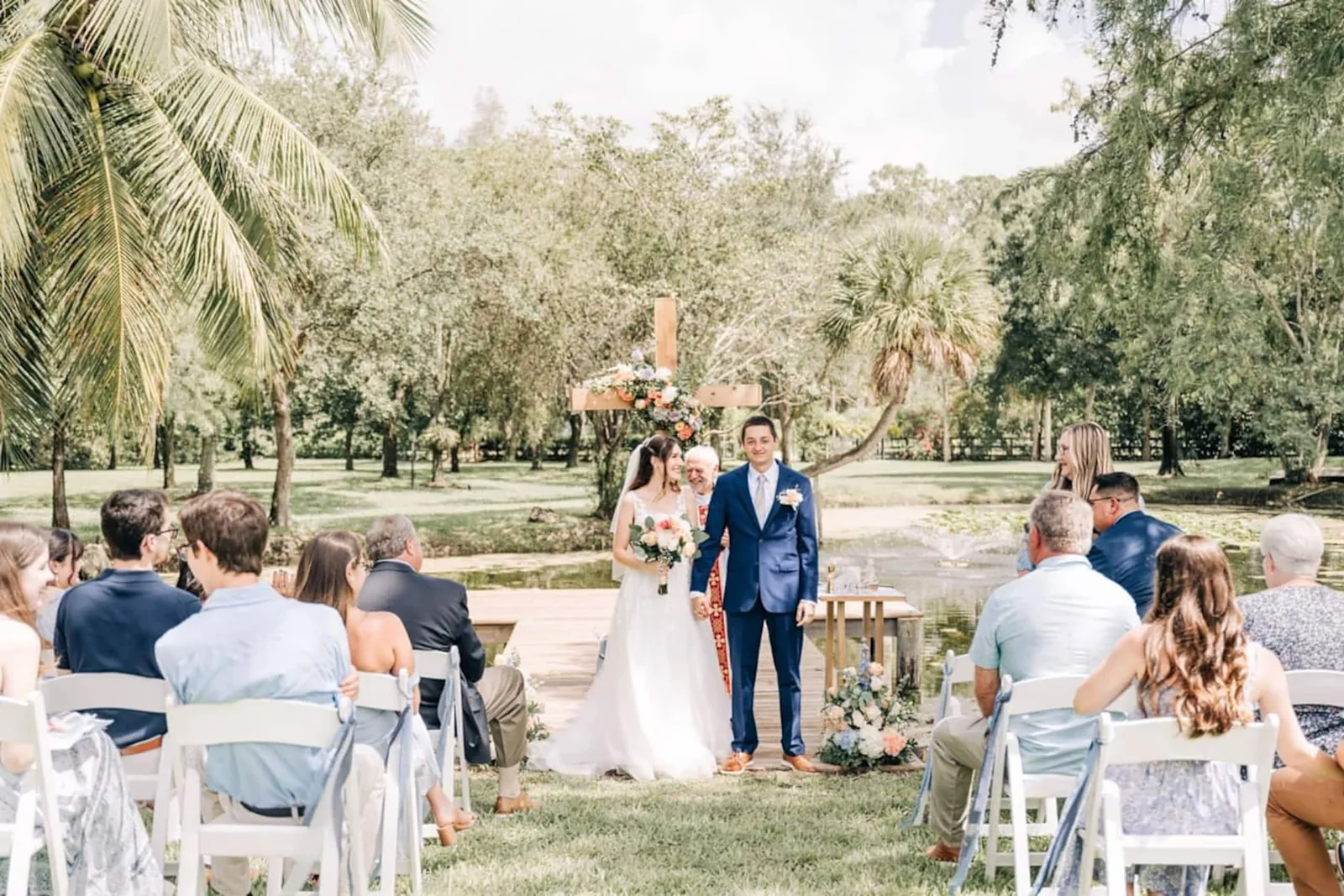 Outdoor ceremony on the lawn under the oaks, guests on white chairs