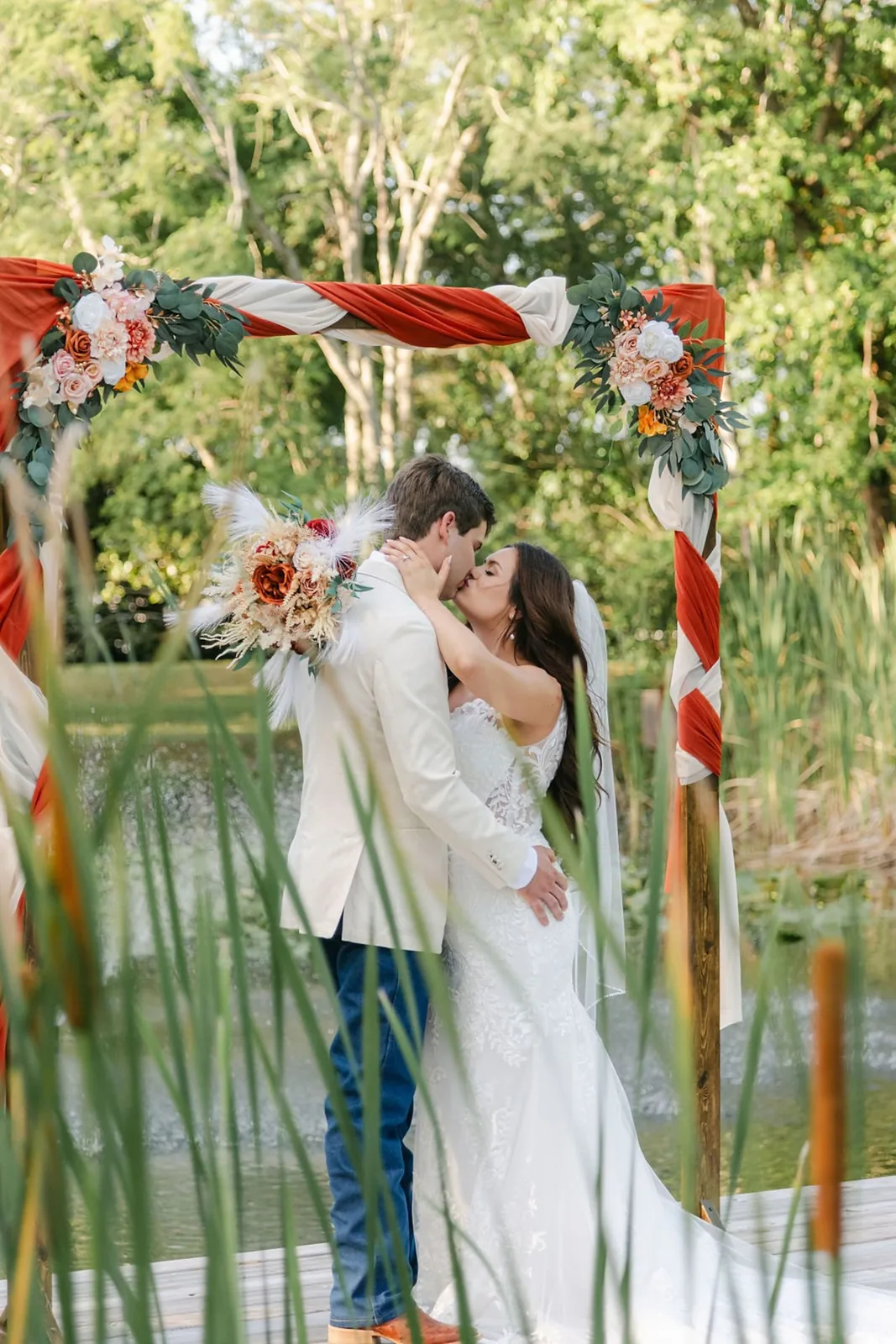 Couple kissing beneath a floral arch