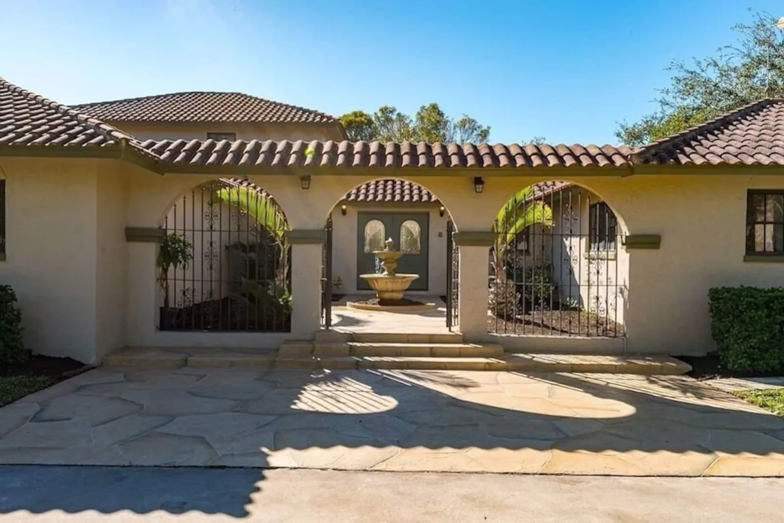Stucco arches and wrought-iron gates at the front of the hacienda, under a terracotta tile roof