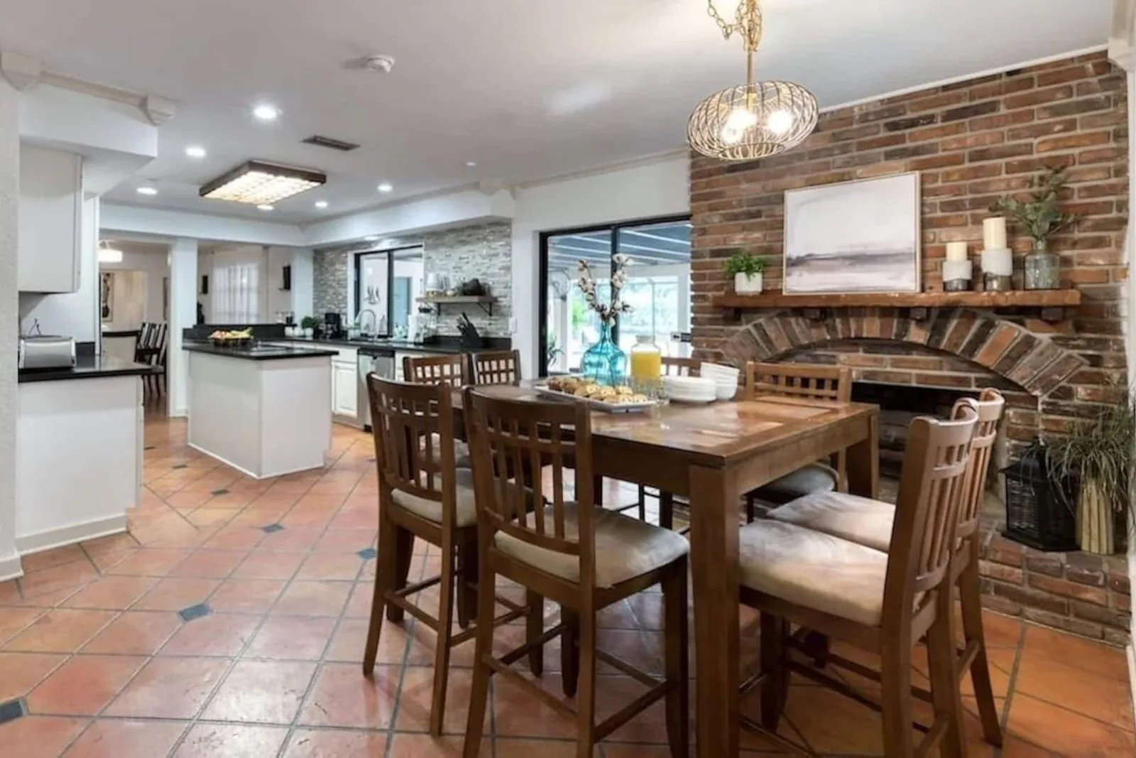 Breakfast table by a decorative brick fireplace, the kitchen beyond