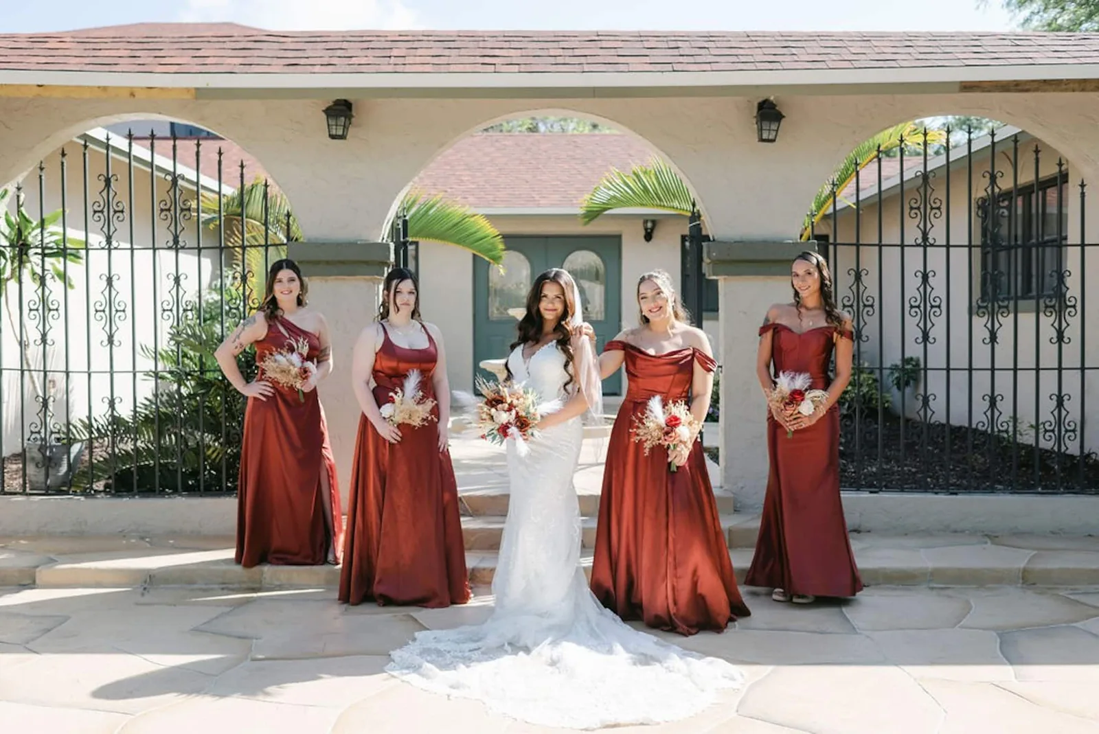 Bride with her bridesmaids in rust-colored dresses at the arches