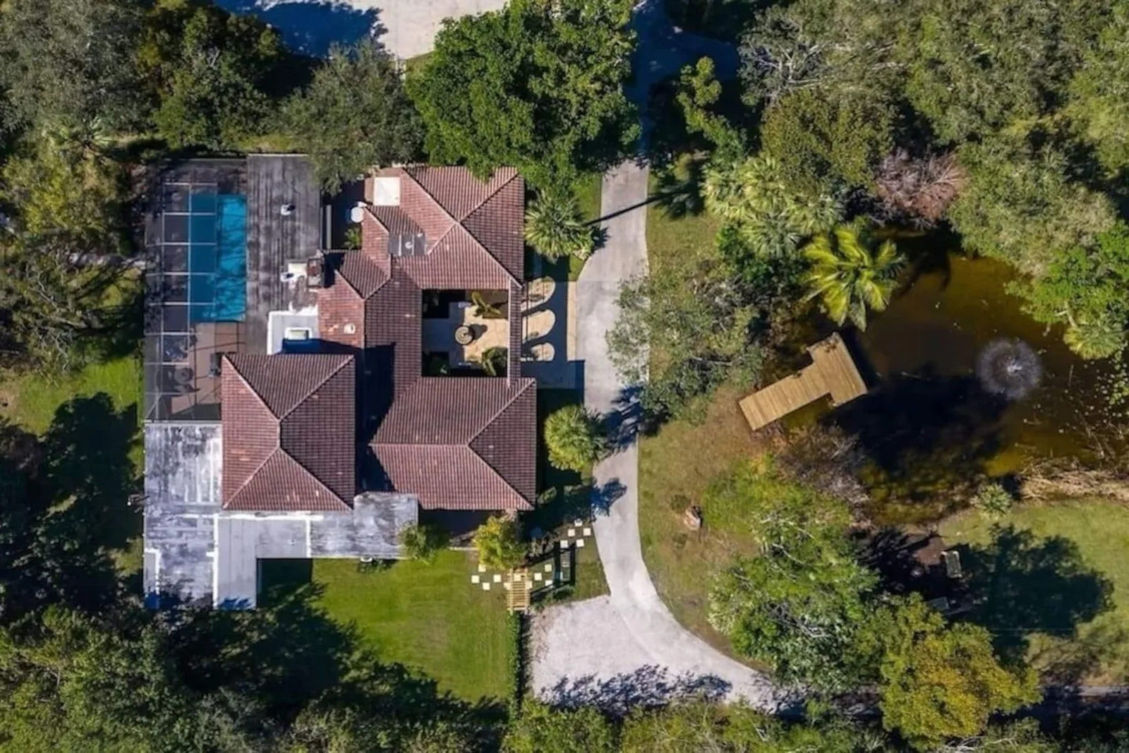 Overhead view of the house, the screened pool and the pond with its dock