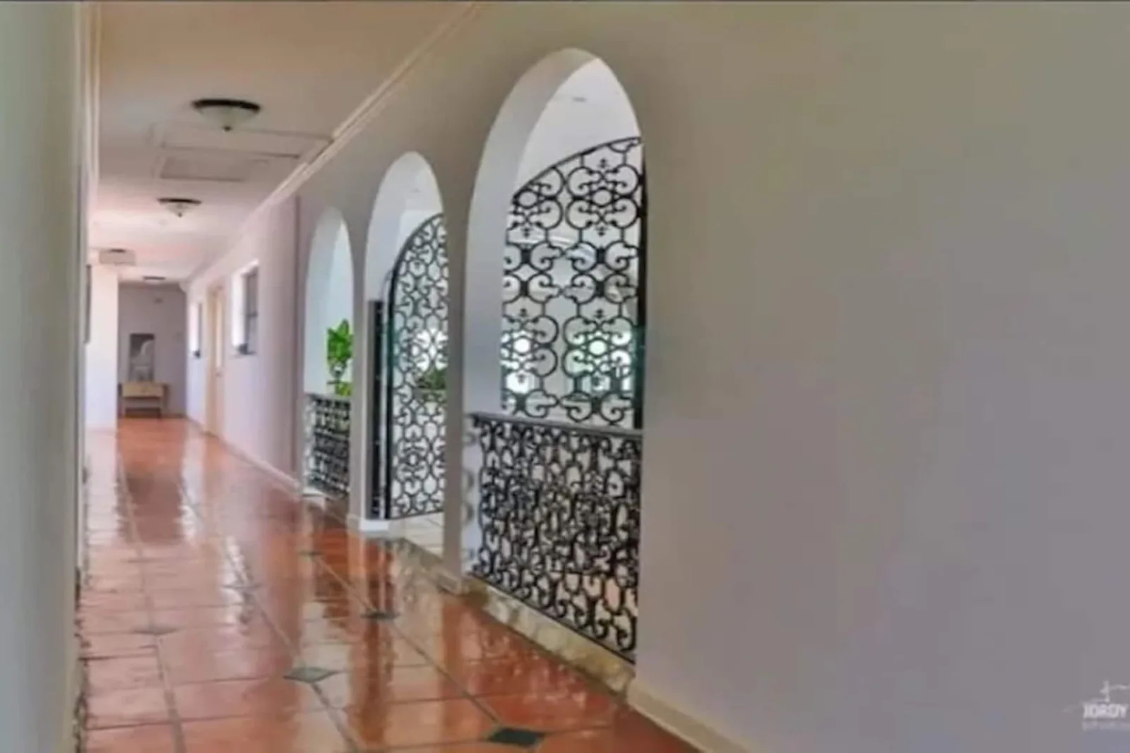 Arched loggia with a terracotta floor and wrought-iron grilles